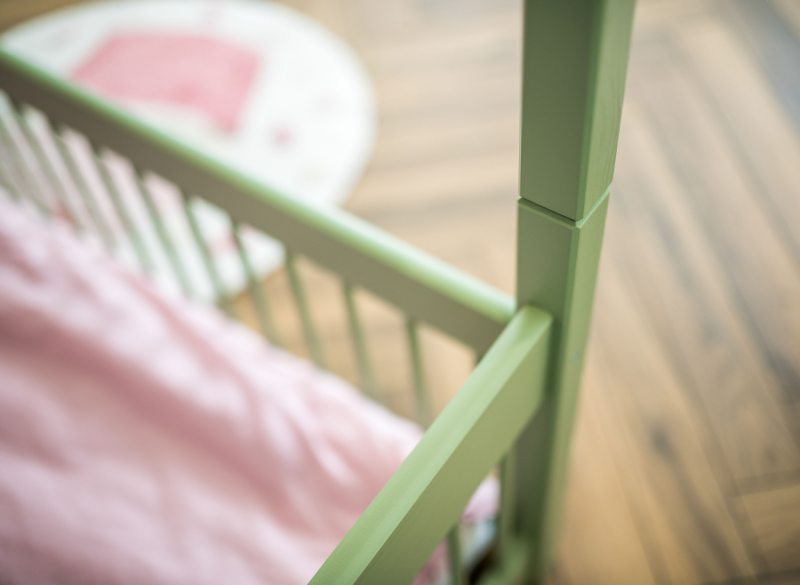 Detale zielonej ramy drewnianego łóżka dziecięcego.