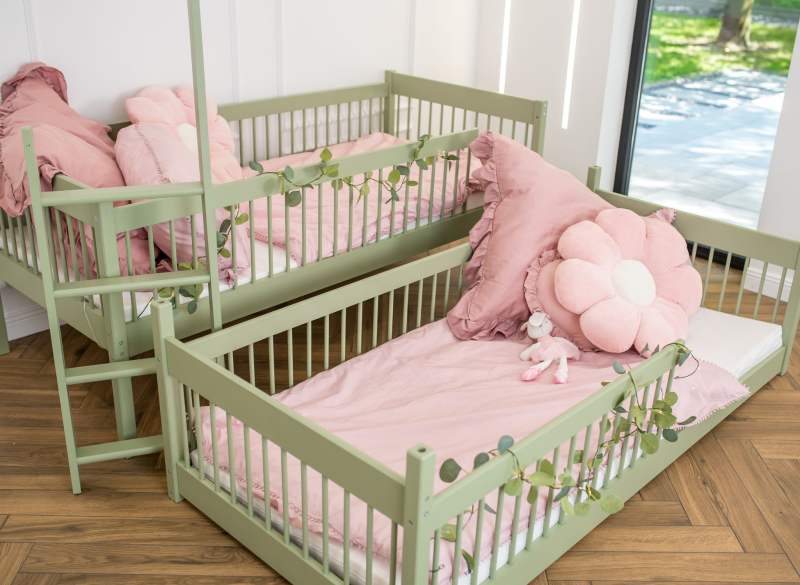 Zestaw dwóch zielonych łóżek dziecięcych z różową pościelą.