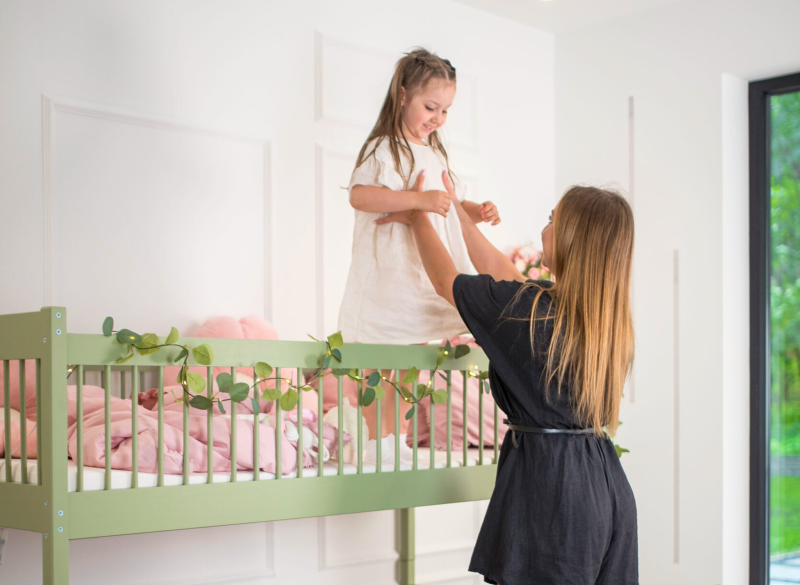 Mama i córka bawiące się przy zielonym łóżku piętrowym.
