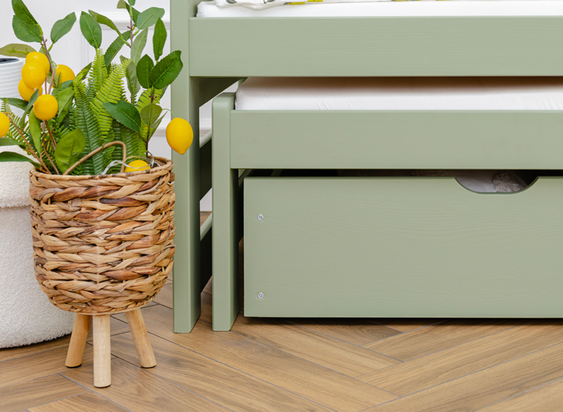 Detal dolnej części zielonego łóżka z wysuwanym dodatkowym spaniem i szufladą.