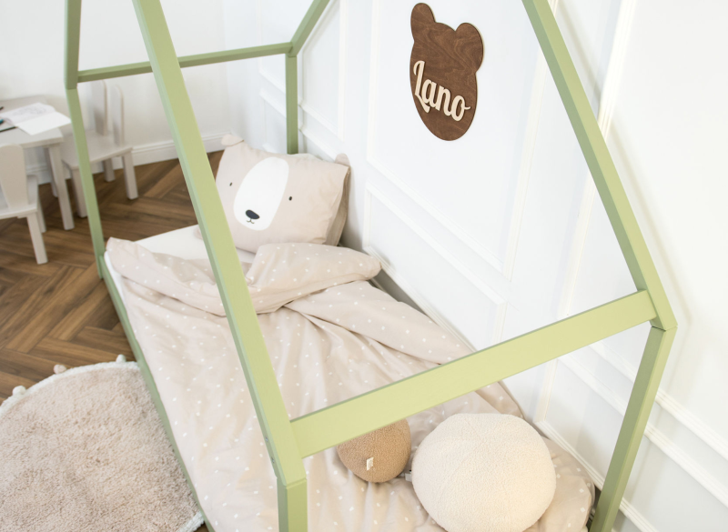 Zielone łóżko domek z drewna w pokoju dziecięcym, beżowa pościel w kropki.