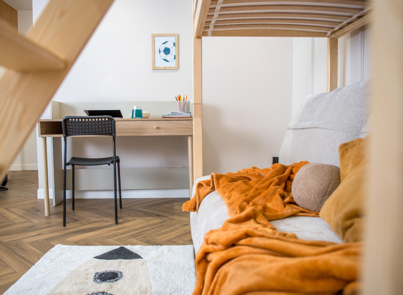 Drewniane biurko i czarne krzesło w pokoju młodzieżowym