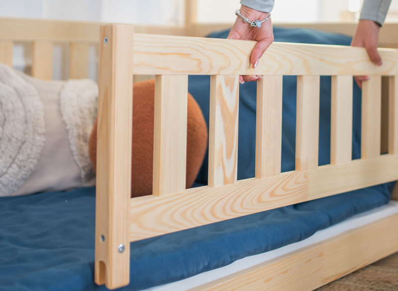 Montaż barierki ochronnej w drewnianym łóżku dziecięcym – naturalne drewno sosnowe.