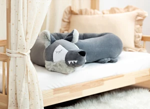 Szary ochraniacz do łóżeczka wilk z puszystymi uszami na jasnym posłaniu.