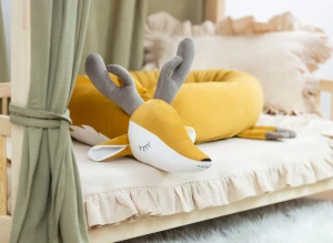 Ochraniacz do łóżeczka w kształcie jelonka w przytulnej aranżacji pokoju.