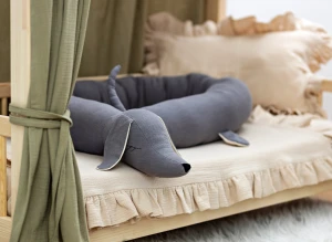 Ciemnoszary ochraniacz jamnik w drewnianym łóżeczku dziecięcym.