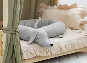 Jasnoszary ochraniacz jamnik w drewnianym łóżeczku dziecięcym.