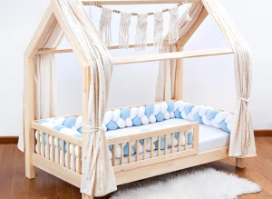 Drewniane łóżko domek dla dziecka z niebiesko-białym ochraniaczem warkoczem.