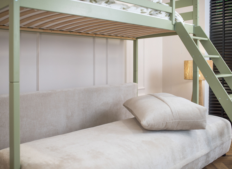 Szara sofa pod szałwiową konstrukcją łóżka piętrowego dla dzieci.