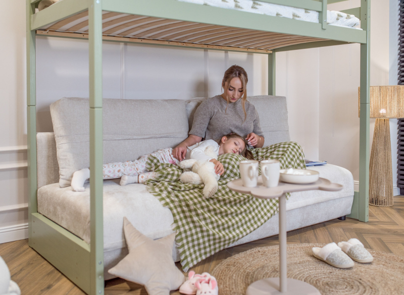Mama i śpiąca córka na sofie pod zielonym łóżkiem na antresoli.