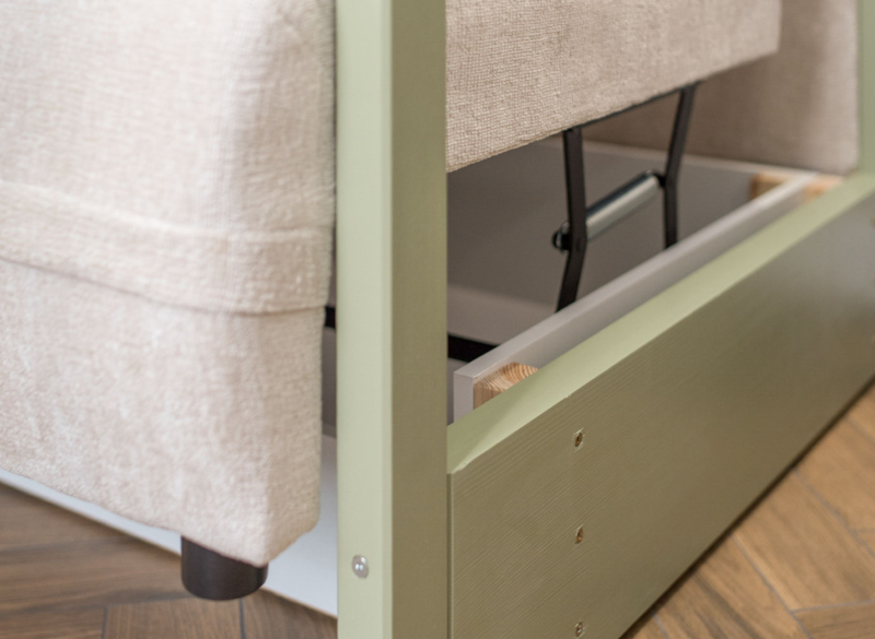 Detal zielonej ramy łóżka z mechanizmem podnoszenia i beżową tapicerką.