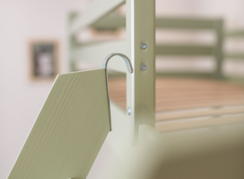 Metalowy hak mocujący drabinkę do zielonej ramy łóżka dziecięcego.