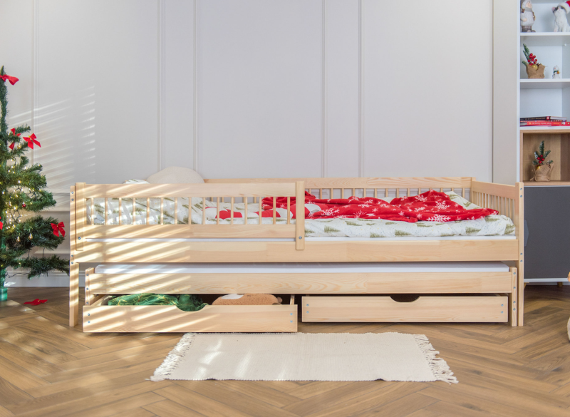 Drewniane łóżko wysuwane z dwiema szufladami w pokoju z choinką.