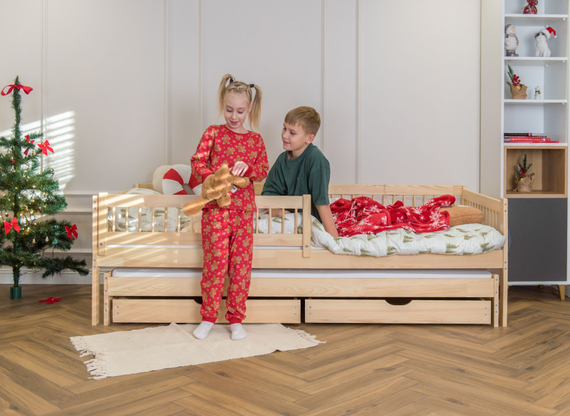 Dzieci w piżamach bawiące się przy sosnowym łóżku wysuwanym.