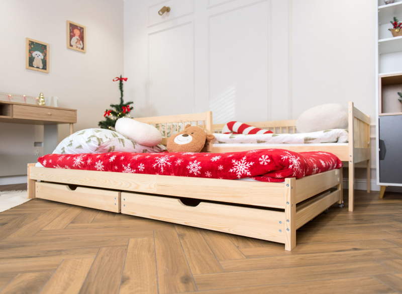 Drewniane łóżko dziecięce z wysuwaną dostawką i świąteczną pościelą.
