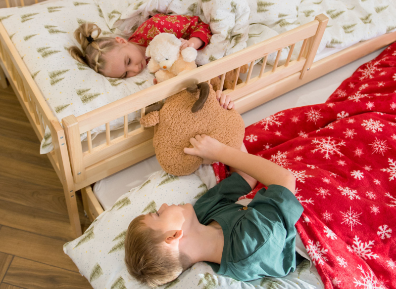 Dzieci odpoczywające w dwupoziomowym łóżku w świątecznej aranżacji.
