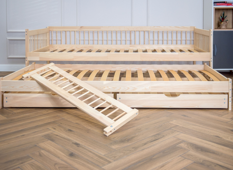 Konstrukcja łóżka dziecięcego z wysuwaną dostawką, szufladami i barierką.