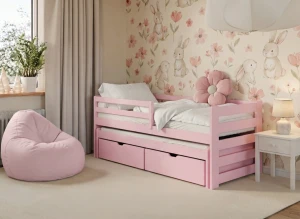 Różowe łóżko dziecięce z wysuwanym spaniem, szufladami i tapetą w zajączki.