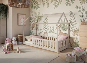 Jasnoszare łóżko domek dla dzieci w pokoju z leśną tapetą i zabawkami.