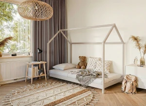 Białe łóżko domek w pokoju dziecięcym w stylu boho z okrągłym plecionym dywanem.