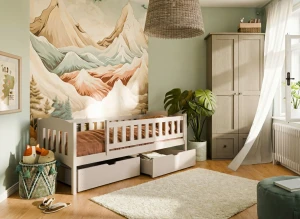 Białe łóżko dziecięce z szufladami w pokoju z motywem górskim.