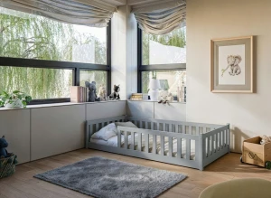 Minimalistyczne szare łóżko dla malucha w przytulnej, jasnej sypialni.