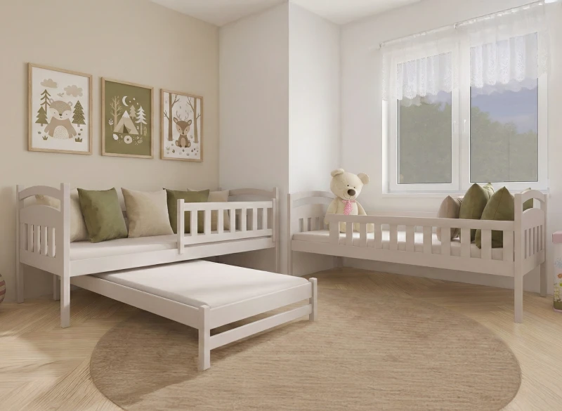 Białe drewniane łóżko dziecięce z wysuwanym spaniem i barierką w przytulnym pokoju.