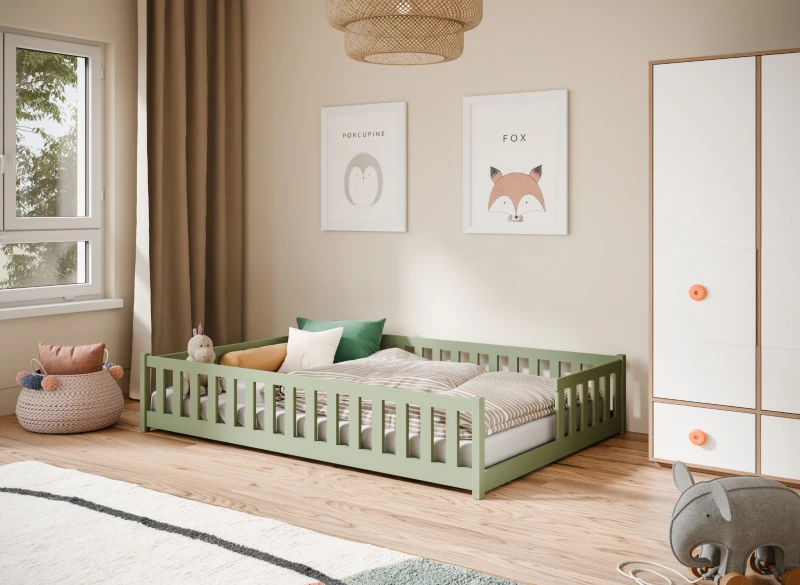 Niskie zielone łóżko dziecięce typu floor bed w przytulnym pokoju z dekoracjami.