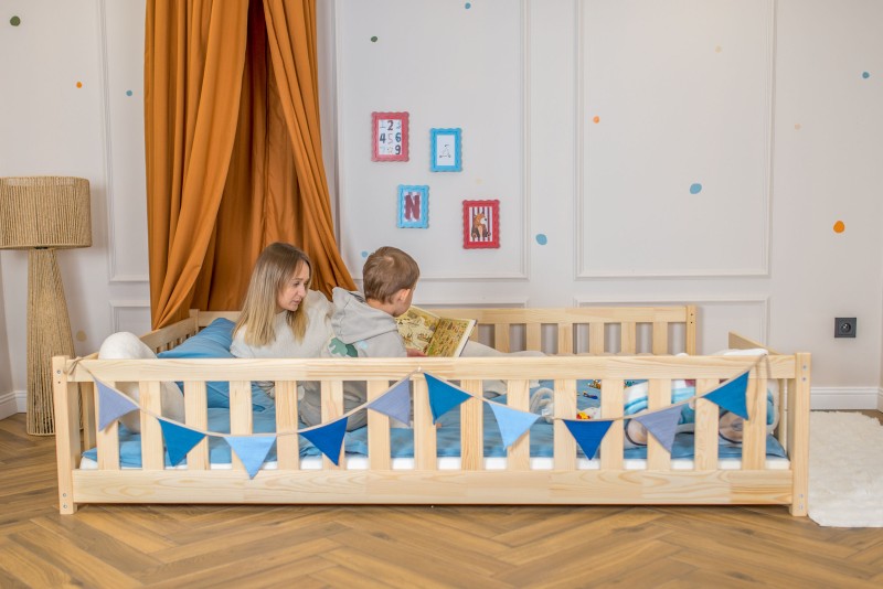 Pokój dziecięcy z drewnianym łóżkiem, baldachimem i mamą czytającą książkę z synem.