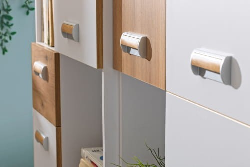 Detal nowoczesnych frontów szafek w kolorze białym i drewna z ergonomicznymi uchwytami.